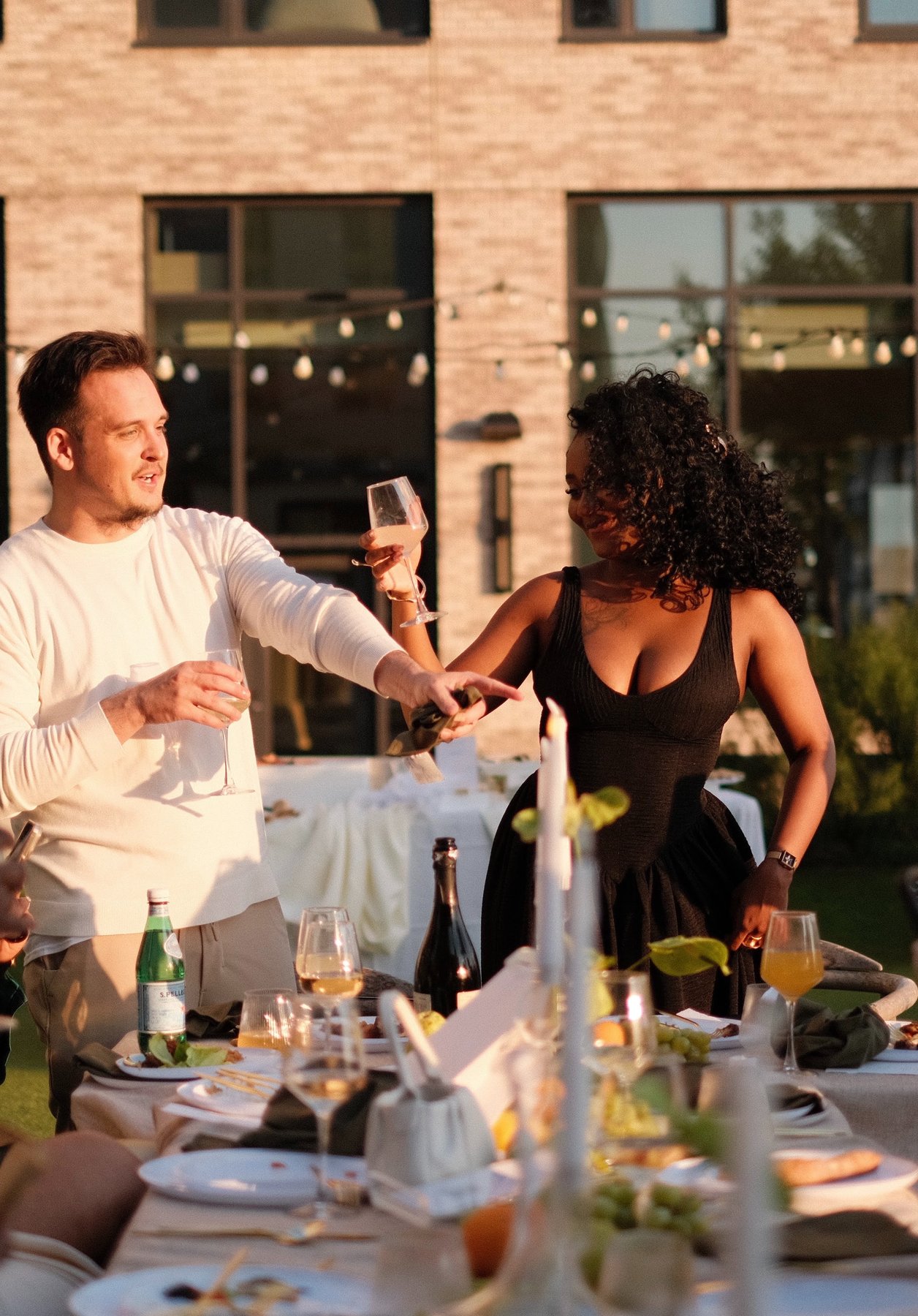 Marie and Matthew raising a glass at a candlelit outdoor dinner