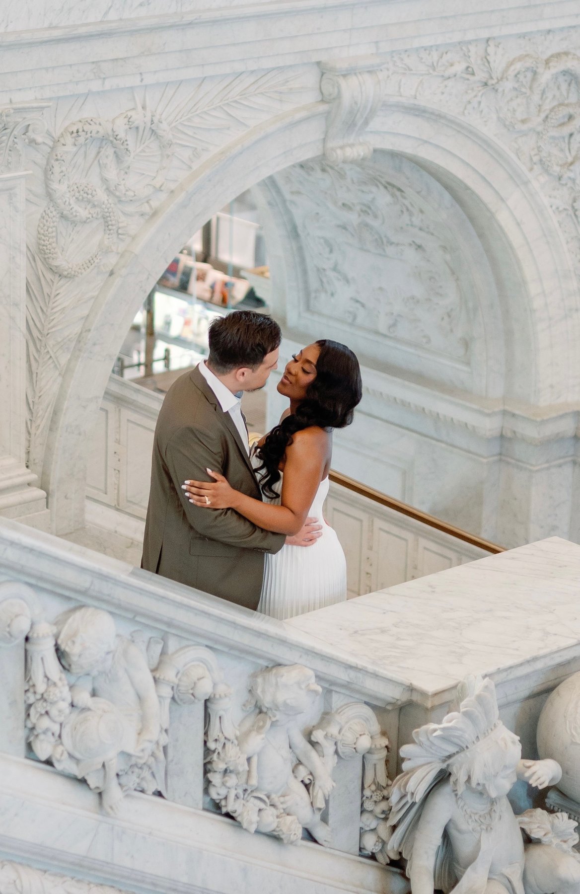 Marie and Matthew embracing on a carved marble staircase